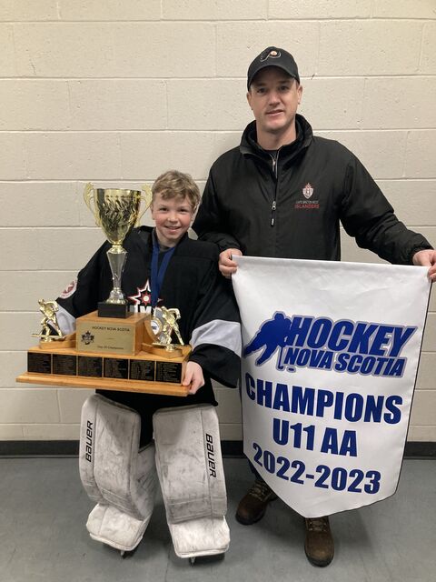 Kenzie Campbell with his son holding the Hockey Nova Scotia U11 AA championship trophy and banner